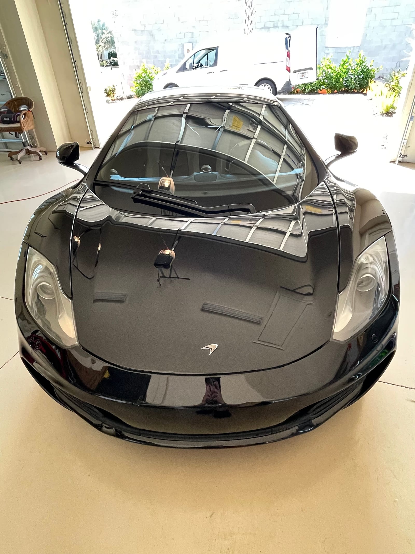 Black McLaren coated front end reflecting the shop doorway